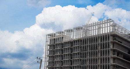 Panoramic view where workers are working on a big construction site and many cranes are working in new building business industry tower cranes in action on blue sky background