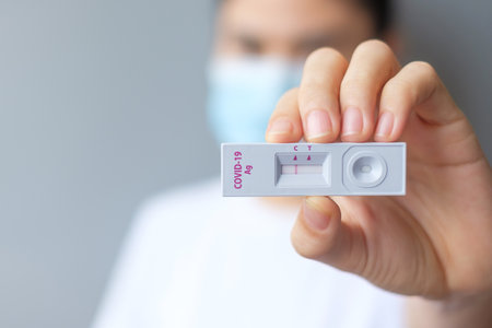 Woman holding rapid antigen test kit with negative result during swab covid-19 testing. coronavirus self nasal or home test, lockdown and home isolation concept