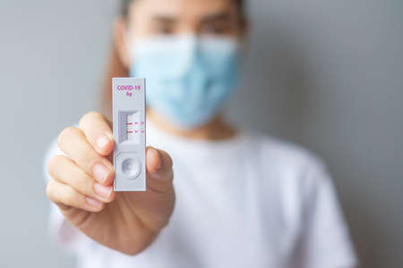 Woman holding rapid antigen test kit with positive result during swab covid-19 testing. coronavirus self nasal or home test, lockdown and home isolation concept Фото со стока