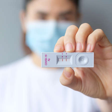 Woman holding rapid antigen test kit with positive result during swab covid-19 testing. coronavirus self nasal or home test, lockdown and home isolation concept