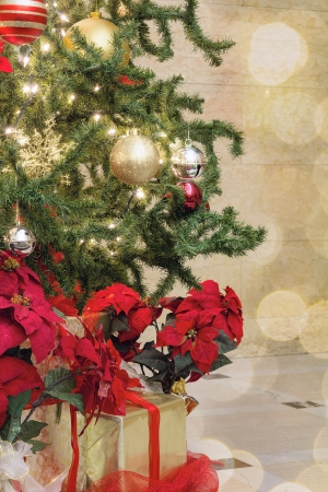 christmas tree decoration with bokeh lights sparkles ornaments ribbons poinsettia and presents under the tree stock - Poinsettia Christmas Tree Decorations christmas tree decoration with bokeh lights sparkles ornaments ribbons poinsettia and presents under the tree stock - Poinsettia Christmas Tree Decorations