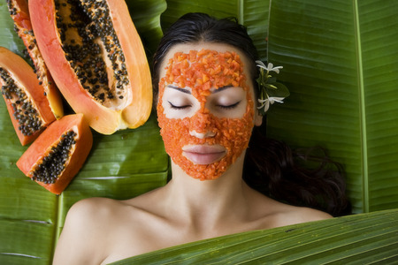 papaya: người phụ nữ xinh đẹp da trắng có đu đủ tươi mặt nạ tự nhiên áp dụng, chăm sóc da và chăm sóc sức khỏe (ngoài trời). vitamin mặt nạ đu đủ lát tại salon spa