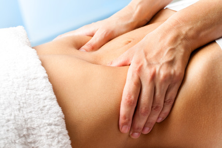 Massage: Макро из рук массирующими женский abdomen.Therapist применяя давление на живот.