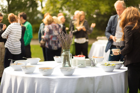 Bankett Mittagspause bei Konferenztreffen auf der Hotelterrasse. Sortiment von Speisen und Getränken. Unerkennbare Leute, die über Lebensmittel im Hintergrund sich besprechen.