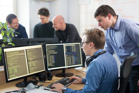 Startup business and entrepreneurship. Young software developers team brainstorming and programming on desktop computer in startup company share office space. Stock Photo - 95872463
