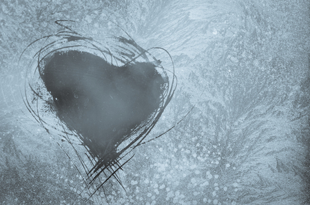 scratched heart shape on frosty pattern on the window