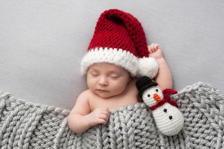 睡眠 2 週齢 新生児 雪だるまぬいぐるみ付けかぎ針編みのサンタ帽子をかぶっている男の子 の写真素材 画像素材 Image