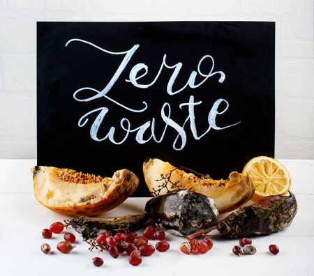 Chalkboard with zero waste lettering and rotten fruits close up