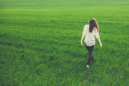 sad lonely: Unrecognizable lonely sad girl walking on summer meadow. Rear view. Sadness and loneliness concept with copy space. Stock Photo