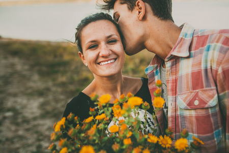 Happy teenage girl being kissed by her boyfriend outdoors. Happy relationship. Lifestyle. Feelings. Love. Фото со стока