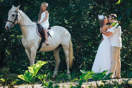 hombre, mujer vestida como una novia, niña y caballo blanco en el