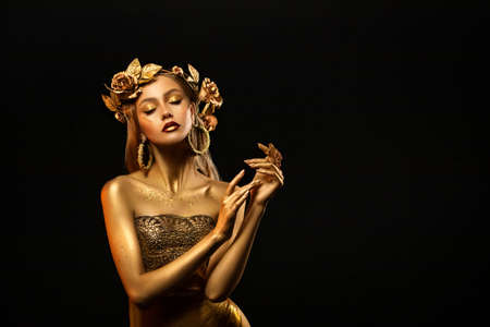 Fantasy portrait of woman, golden skin body. girl goddess in wreath, gold roses, dress. beautiful face steel glitter art makeup. artistic photo dark black background. girl princess. fashion model pose