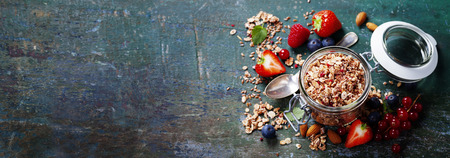 Petit-déjeuner sain composé de muesli, de baies avec du yaourt et de graines sur fond sombre - aliments sains, régime alimentaire, détoxification, concept propre et végétarien.