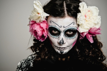 A woman in halloween costume and skull makeup holding flowers Imagens