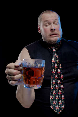 Comic actor man in cap with braids with a glass of beer on a black background, in anticipation of Christmas and New Year Stock Photo