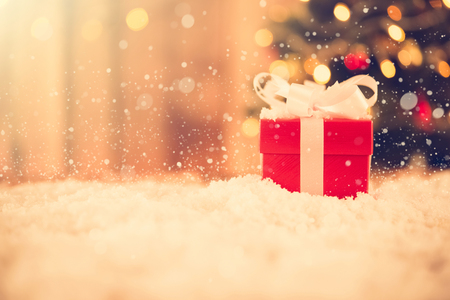 Small Red Gift Box In The Snow With Blur Christmas Tree Background Vintage Tone Small Red Gift Box In The Snow With Blur Christmas Tree Background Vintage Tone