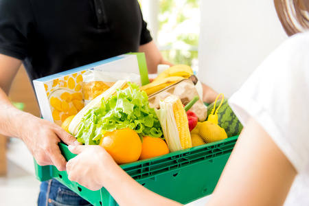 Delivery man delivering food to a woman at home - online grocery shopping service concept