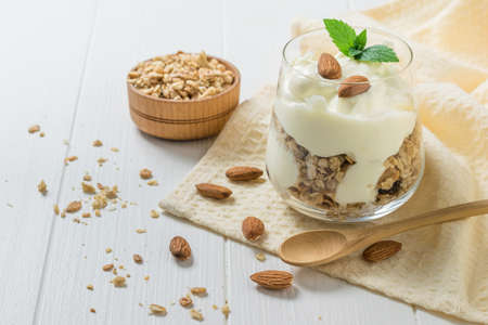 Mała drewniana łyżka obok szklanki jogurtu i muesli. wegetariańskie jedzenie z prebiotykami. Zdjęcie Seryjne