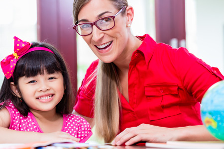 Teacher giving language lessons and doing homework to Chinese child