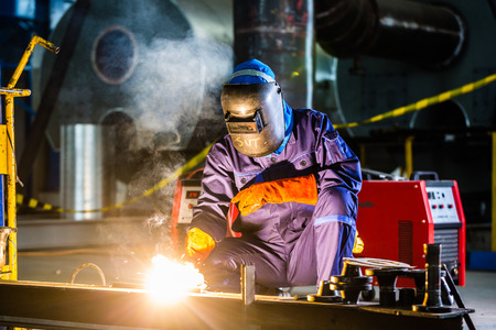 Welder working in an industrial setting manufacturing steel equipment - 37847125