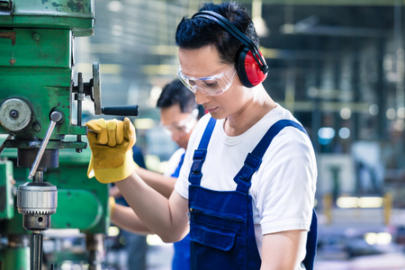 factory production operator asian worker in production plant drilling at machine on the factory floor - Production Operator factory production operator asian worker in production plant drilling at machine on the factory floor - Production Operator