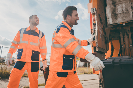 Two garbagemen working together on emptying dustbins for trash removal