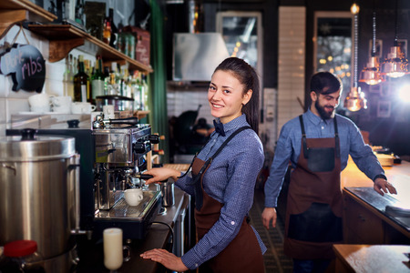 girl barista bartender waiter in uniform making coffee at the bartender barista