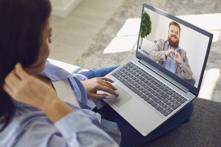 Date online. loving couple. funny man looking at the camera smiling holds his hands in the shape of a heart video chat call using laptop romantic application at home. st. valentines day.