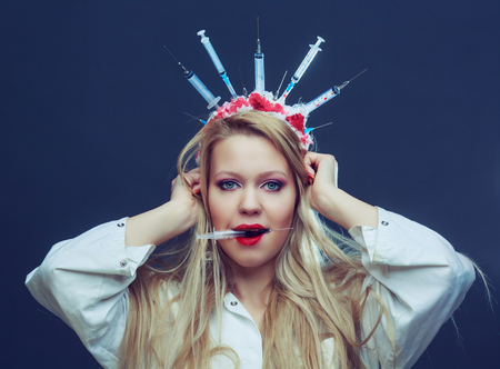 Halloween costume of a crazy nurse with crown made of syringes and a syringe in the hand