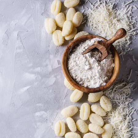 生の未調理のジャガイモは 小麦粉のオリーブウッドボウル 灰色のコンクリートの背景の上にすりおろしたパルメザンチーズをニョッキ コピースペース付きの上面図 家庭料理 の写真素材 画像素材 Image