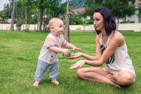 the little boy learns to stand on his feet mom helps my child