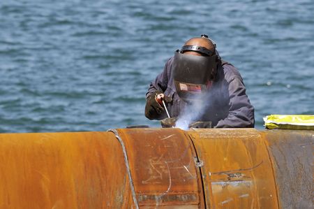 Worker welding two big pipes in a harbour Фото со стока