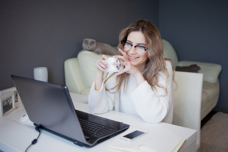 学生やフリーランサー ラップトップで自宅で働く 魅力的な若い女性は コーヒーのカップでモニターの前に座っています の写真素材 画像素材 Image