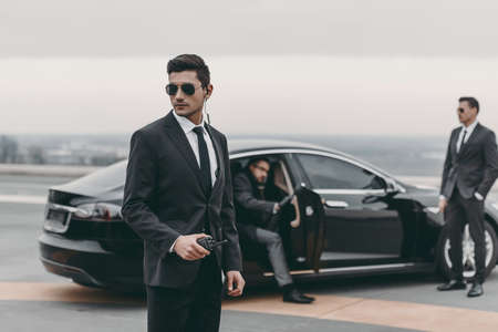 bodyguard with portable radio standing at businessman car