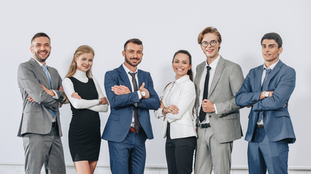 Smiling businesspeople with crossed arms posing near board after training in hub and looking at camera Stock Photo
