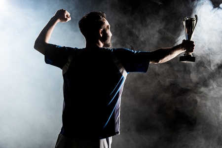 Silhouette of champion holding trophy on black with smoke Stock Photo