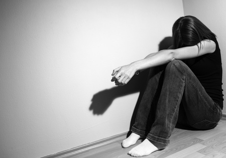 sad lonely: Young woman suffering from a severe depression (very harsh lighting is used on this shot to underlineconvey the gloomy mood of the scene) Stock Photo