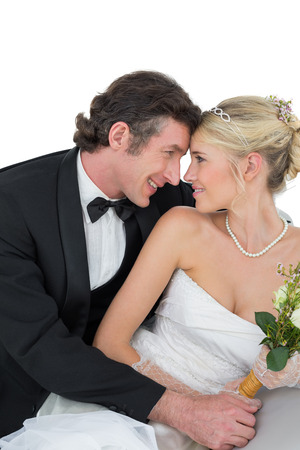 attractive bride and groom with head to head against white