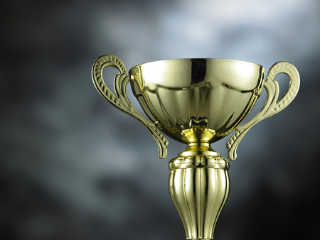 Classic golden trophy on the gray background with light effect