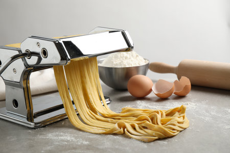 Machine à pâtes avec pâte et produits sur table grise