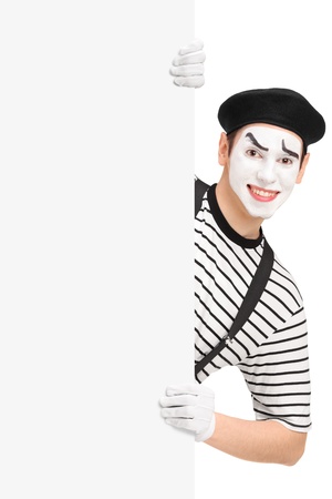 Smiling mime artist posing behind a blank panel isolated on white background