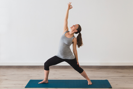 Young pregnant woman in reverse warrior yoga posture
