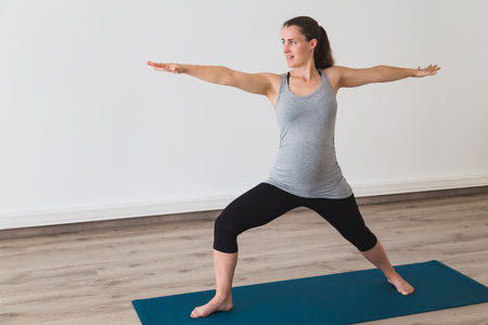 Young woman doing prenatal yoga in warrior two pose Stock Photo