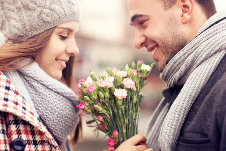 A picture of a man giving flowers to his lover on a winter day Фото со стока