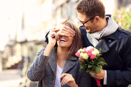 Picture of young man surprising woman with flowers