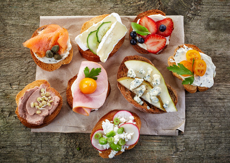 collection of toasted bread slices with various cheese and meats, top view Фото со стока