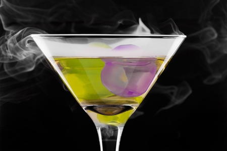 Wine glass with colored ice cubes and floated ice vapor on black background