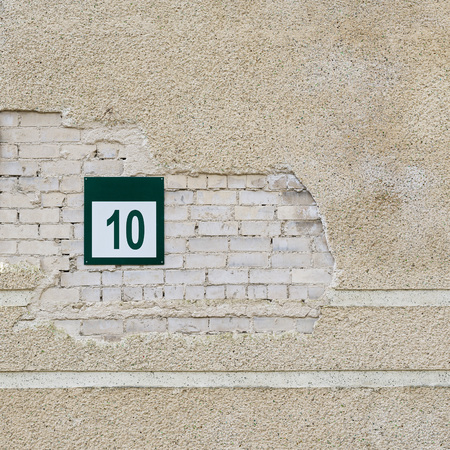 Cracked brick wall and plate with a number ten Фото со стока Cracked brick wall and plate with a number ten Фото со стока