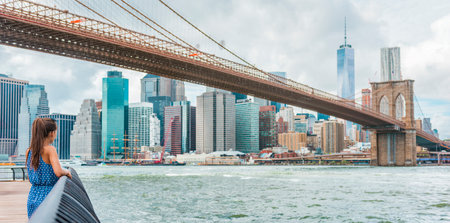 New york city woman looking at view of downtown manhattan skyline from brooklyn park living new york lifestyle walking during summer in usa young professional looking at skyline with aspirations Stock Photo