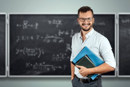 Portrait of a young male teacher on the background of the school blackboard. teacher's day knowledge day back to school study online learning